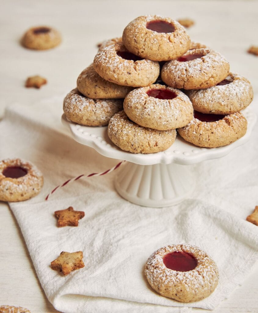 A plate of golden-brown Thumbprint Cookies filled with a variety of colorful jams.