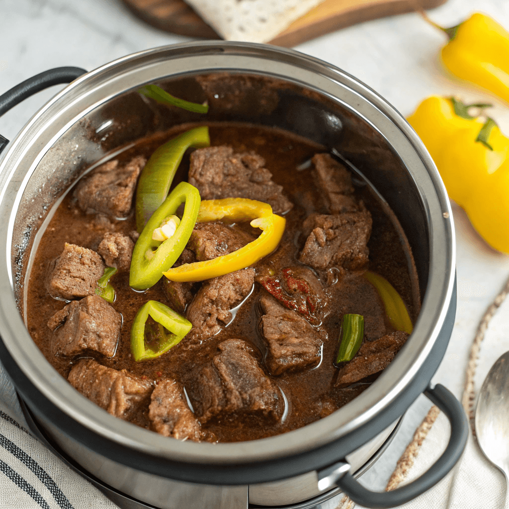 Bright yellow pepperoncini peppers scattered over the beef in the Instant Pot.